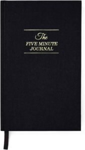 A black cover journal with the words 5 minute journal on it. A Must have for homeschooling moms. 
